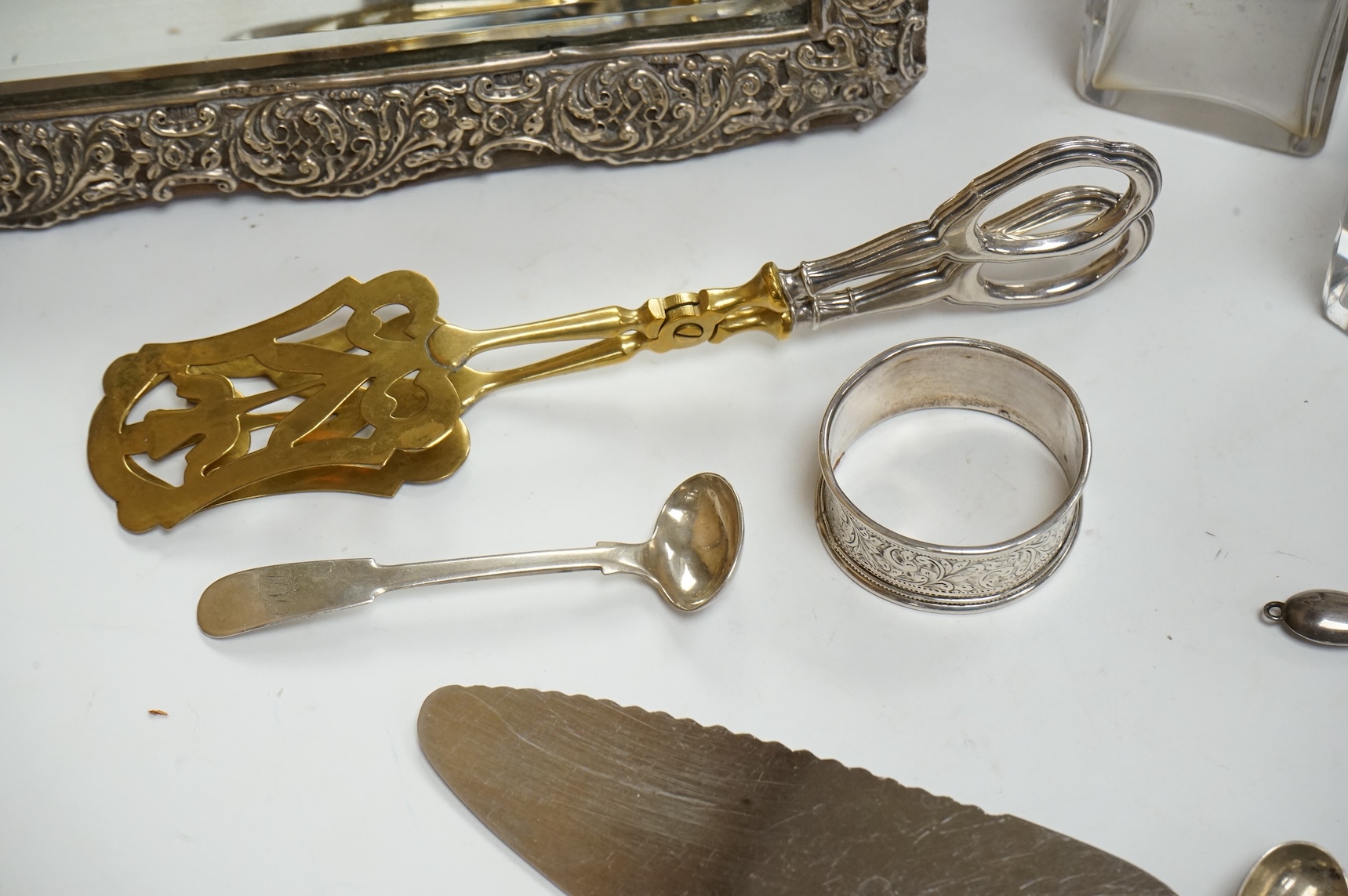 A late Victorian repousse silver mounted rectangular easel mirror, Birmingham, 1896, 35.7cm(a.f.), together with a modern silver mounted photograph frame, a silver handbag mirror/compact, three mounted glass toilet jars,